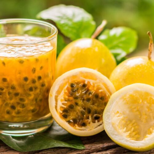 passion fruit tea in glass. beside the glass paasion fruit on the surface.