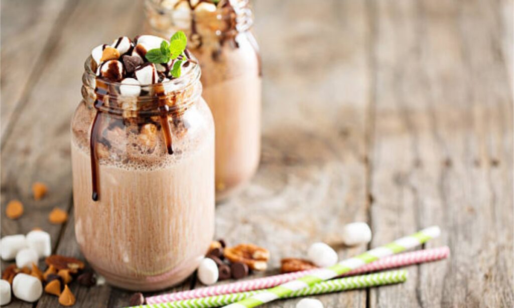 nutella milkshake in the jar, beside the jar straw on the surface.