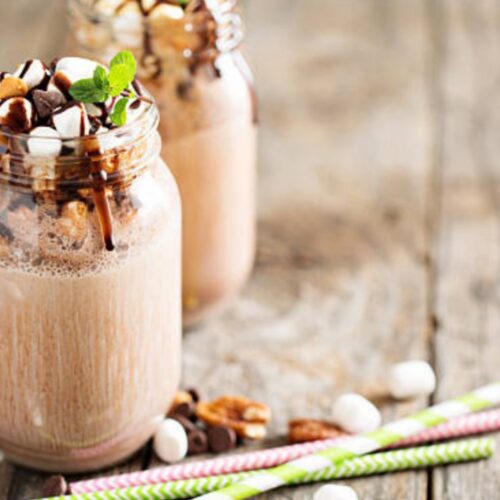 nutella milkshake in the jar, beside the jar straw on the surface.