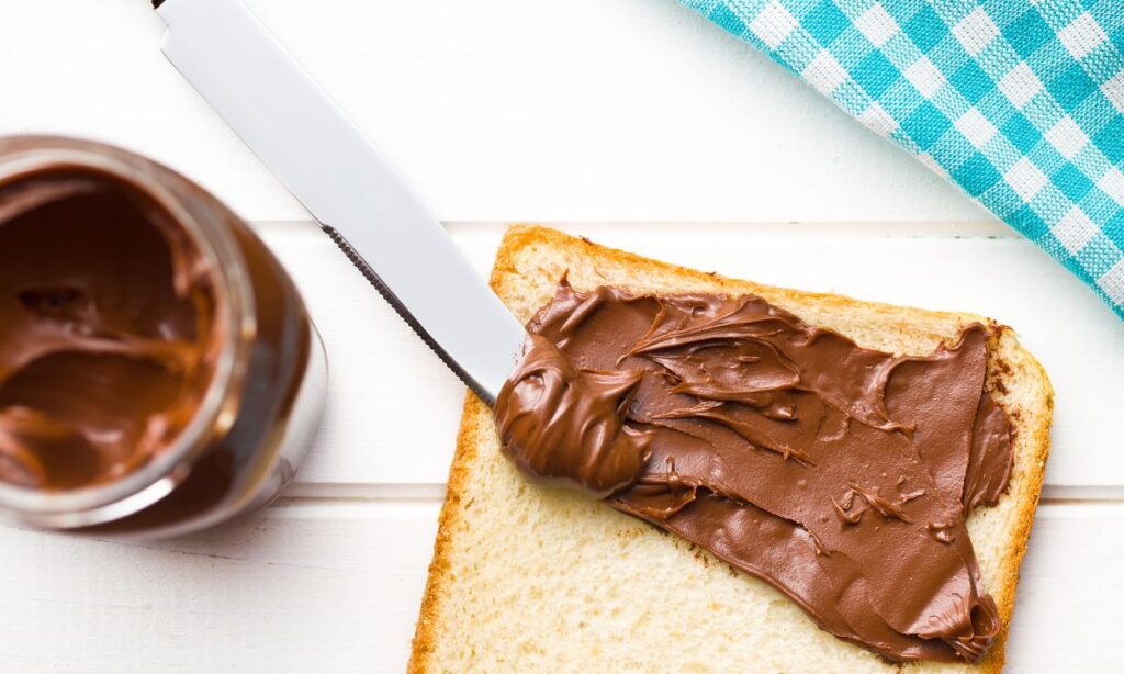 nutella sandwich on surface, beside the bread nutella box on the surface.