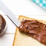 nutella sandwich on surface, beside the bread nutella box on the surface.