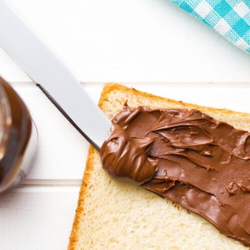 nutella sandwich on surface, beside the bread nutella box on the surface.