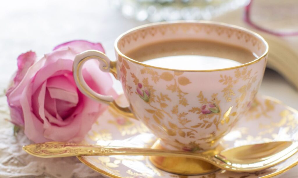 pink in cup, beside the cup spoon and rose on the plate.