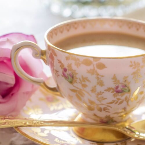 pink in cup, beside the cup spoon and rose on the plate.