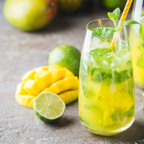 mango mojito in glass with ice cubes and mint leaves.