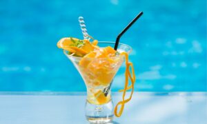 orange mojito in glass with black color straw.