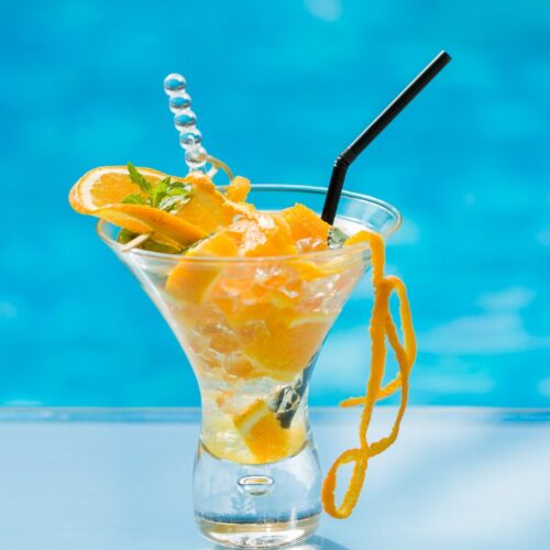 orange mojito in glass with black color straw.