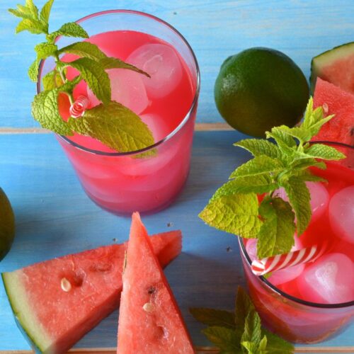 watermelon mojito in glass with ice cubes and mint leaves. watermelon slices on the surface.