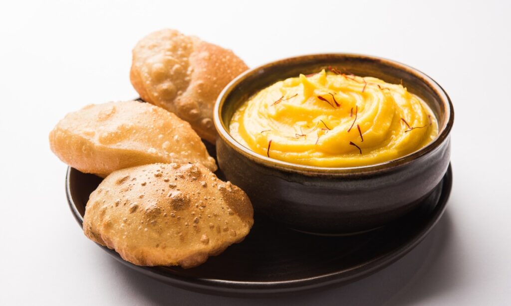 bowl of mango shrikhand and puri in plate on tableware. mango shrikhand recipe