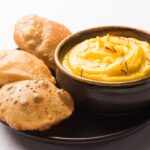 bowl of mango shrikhand and puri in plate on tableware. mango shrikhand recipe