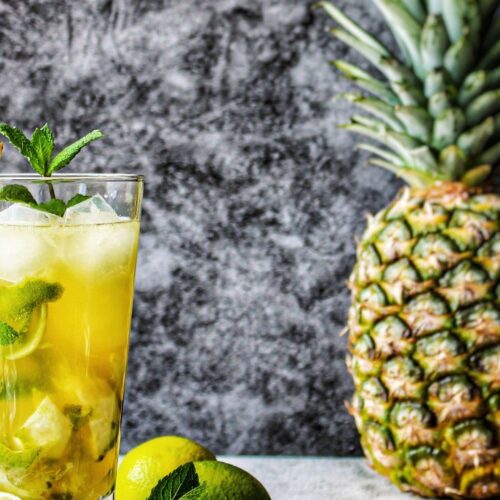pineapple mojito in glass with ice cubes, mint leaves and straw. Pineapple on the surface.