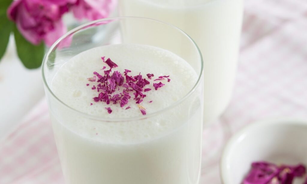 rose lassi in glass with rose petals on tableware. rose lassi recipe