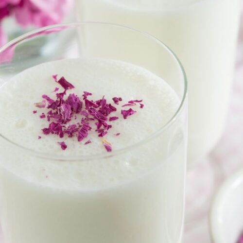 rose lassi in glass with rose petals on tableware. rose lassi recipe