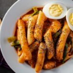 Tteokbokki or spicy rice cakes in white color bowl. Bowl on the tableware.