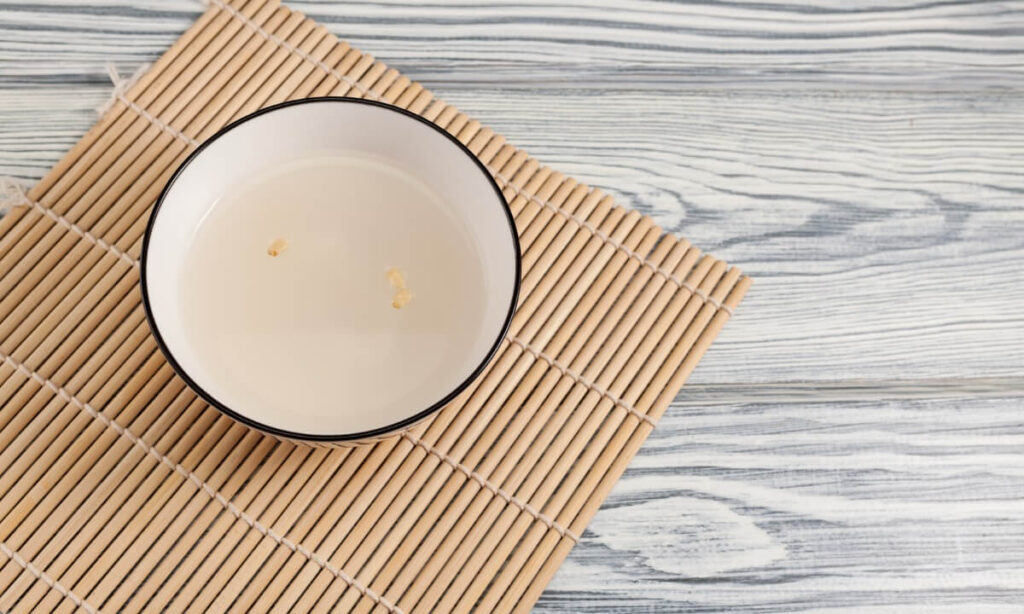 Sikhye or korean sweet rice drink in white color bowl which is on the tableware.