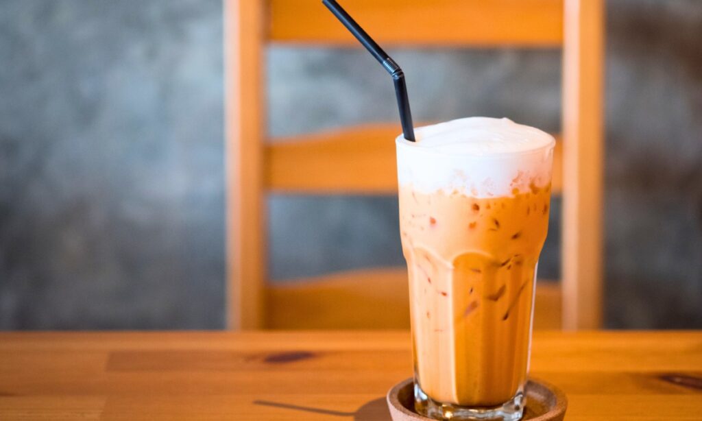 iced thai milk tea in glass with black color straw.