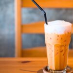 iced thai milk tea in glass with black color straw.