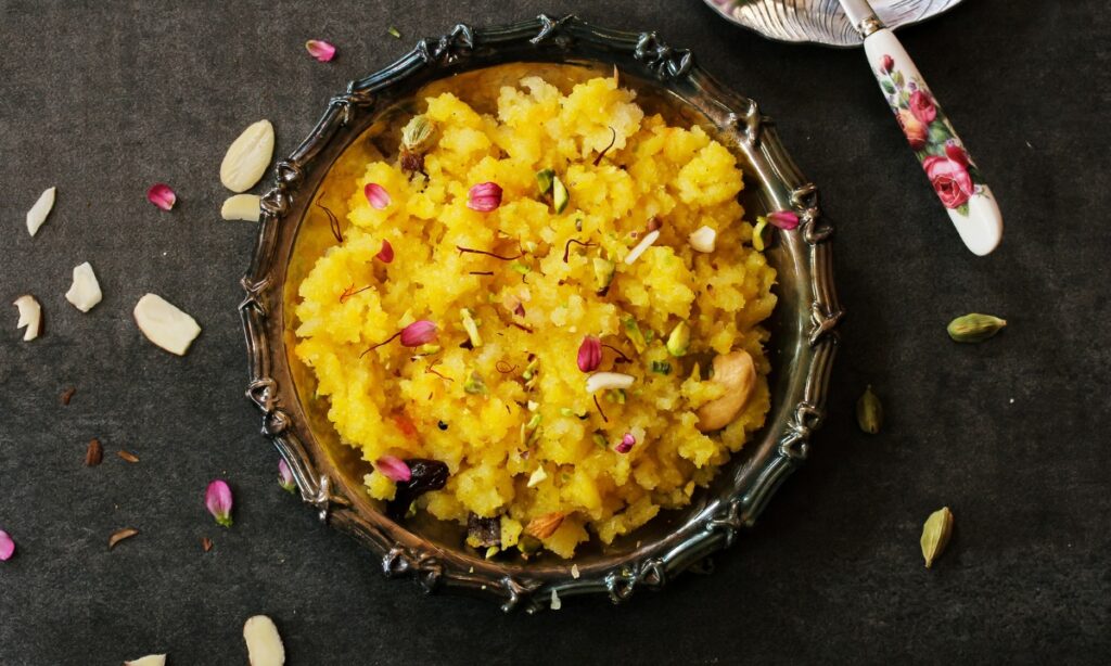 orange halwa in black color bowl.