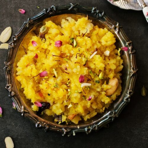 orange halwa in black color bowl.